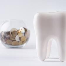 fake tooth next to a bowl of coins