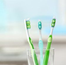 Three toothbrushes sitting in a clear cup