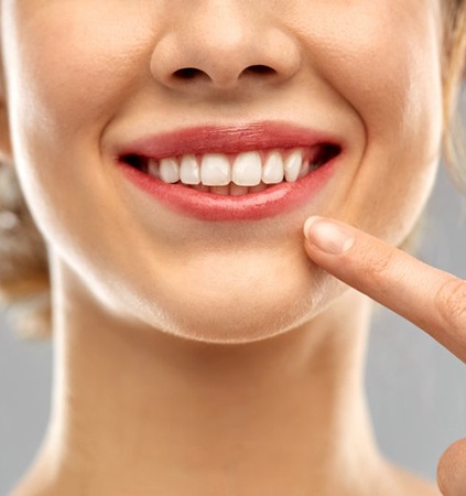 close up woman pointing to her white teeth 