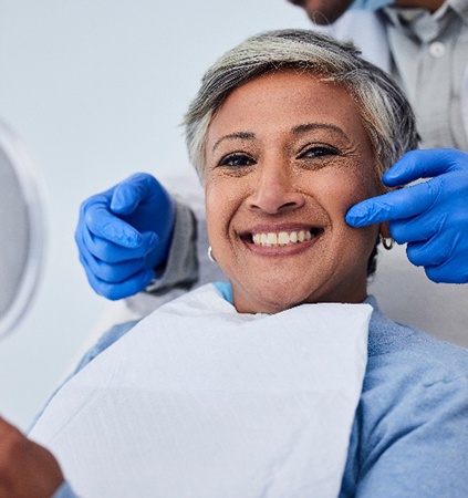 Closeup of woman smiling while holding handheld mirror