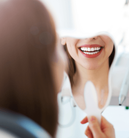 Woman looking at her smile with porcelain veneers