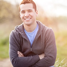Man in grey hoodie smiling with his arms folded