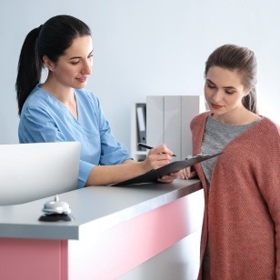 Dental team member showing forms to a woman at front desk