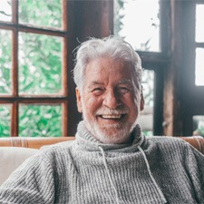 Older man smiling on the couch with dentures   