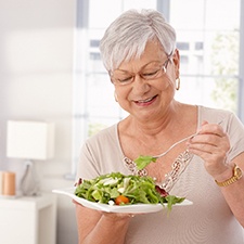Senior woman smiling and eating a salad