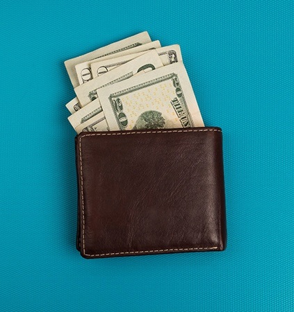 Wallet with money sticking out on blue background