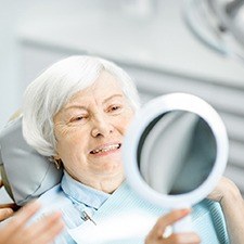 Older woman smiling after getting dentures in Richmond