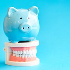 light blue piggy bank sitting on top of a set of false teeth