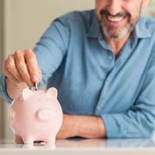 Man saving money in piggy bank for dental emergencies in Richmond