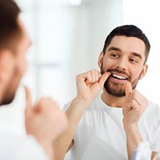 a man flossing to prevent dental emergencies in Richmond