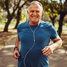 Older man with dental implants in Richmond running