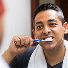 man brushing teeth in front of mirror