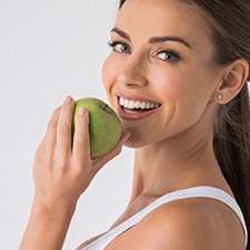 woman biting into green apple