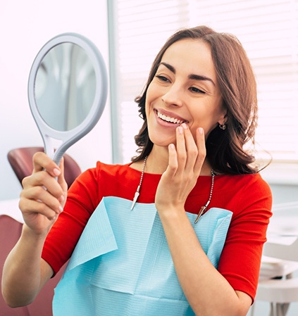 Woman smiling at reflection in dentist's office