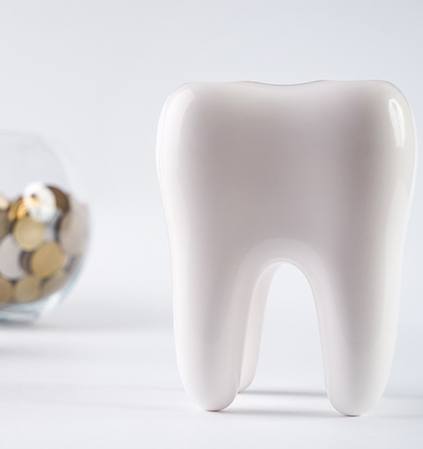 Fake tooth next to stack of coins