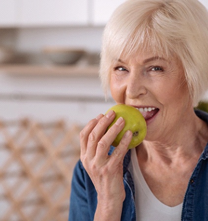 Older woman biting into an apple