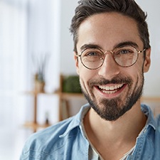 Bearded man with glasses standing and smiling