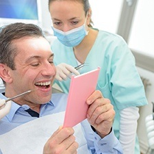 dental patient admiring his new smile in a mirror