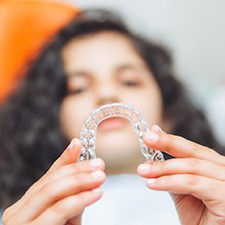Closeup of teen holding clear aligner