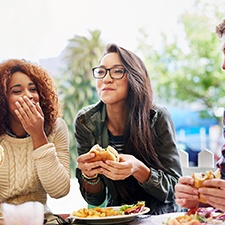 Group of friends smiling while eating lunch