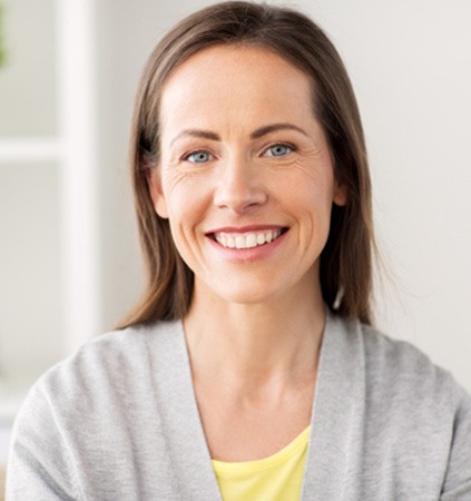 Woman in light grey jacket sitting and smiling