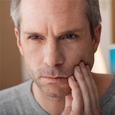 Man feeling his jaw while looking concerned