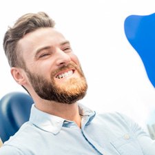Bearded man at the dentist’s office checking smile in mirror