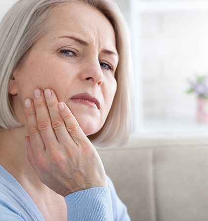 Woman rubbing her jaw and looking concerned