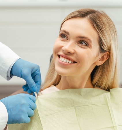 Female patient sitting in chair and smiling at dentist