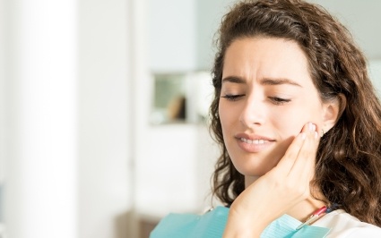 Woman in need of emergency dentistry holding cheek