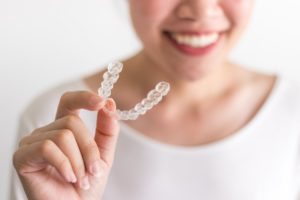 person holding an Invisalign aligner in their hand 