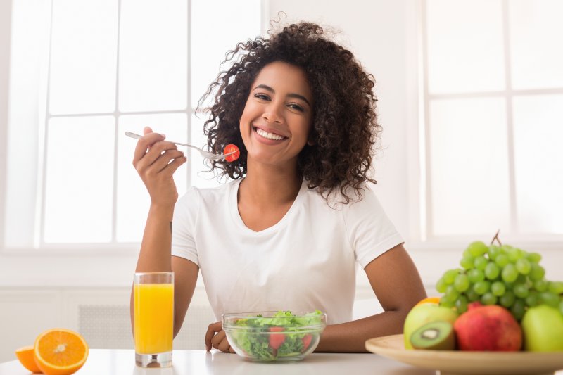 Smiling woman eating salad after dental implant surgery in Patterson