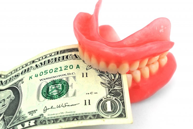 Pair of dentures holding a dollar bill