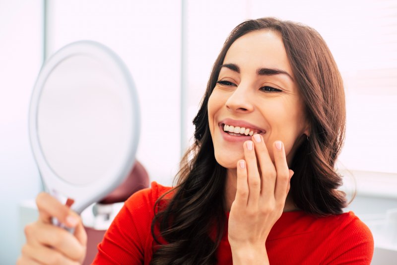 A woman looking at her new dental implants in the mirror