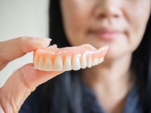 Person holding denture in close-up. 