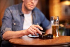 man smoking and drinking alcohol