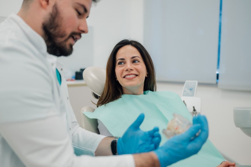 A dentist showing dentures to a smiling woman